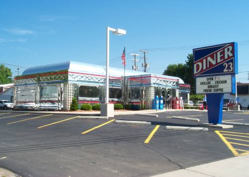 A shiny, retro-style diner with a colorful exterior and a sign reading "Diner 23," set in a parking lot.