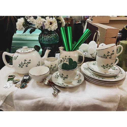 A vintage tea set with green floral patterns, surrounded by decorative items and green accessories on a table.