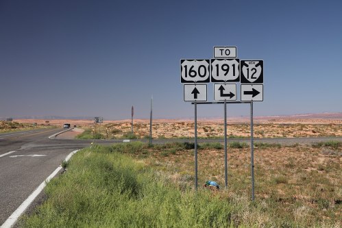 Road sign indicating directions to highways 160, 191, and 12, with a clear blue sky and desert landscape in the background.