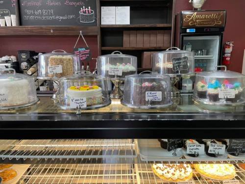 A display case filled with various cakes and desserts under glass domes in a bakery.