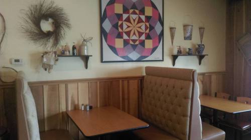 Cozy restaurant interior featuring a geometric wall art, wooden paneling, and a booth with a small table.