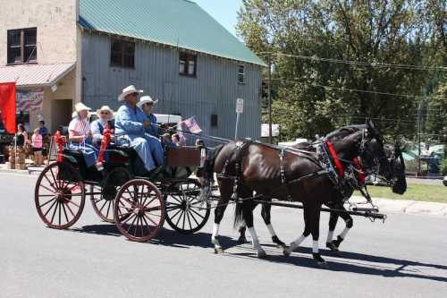 A horse-drawn carriage with passengers in hats parades down a street, surrounded by spectators and buildings.