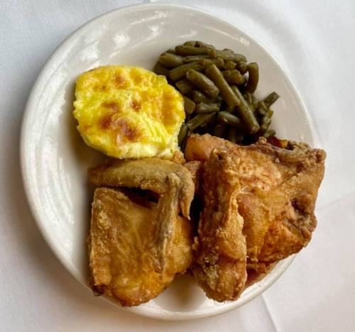 A plate of fried chicken, green beans, and a cheesy baked dish.