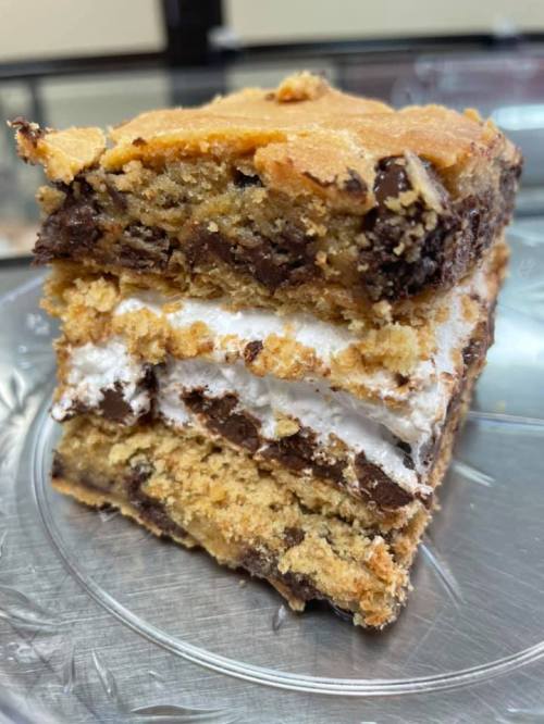 A close-up of a layered dessert with chocolate chips and marshmallow, stacked on a silver plate.