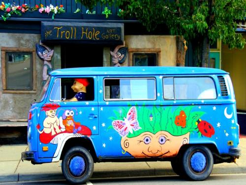 A colorful, painted van parked outside the Troll Hole Art Gallery, featuring whimsical designs and playful characters.