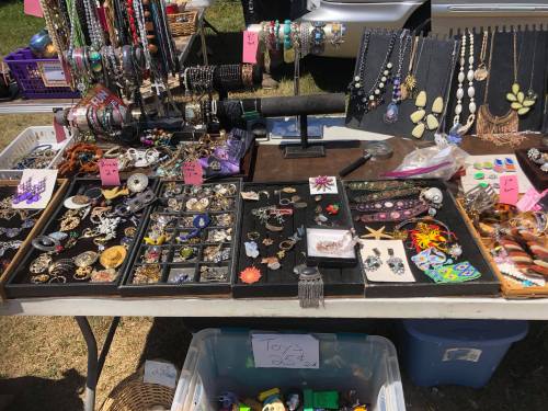 A vibrant display of jewelry, including necklaces, bracelets, and earrings, arranged on tables at a market.
