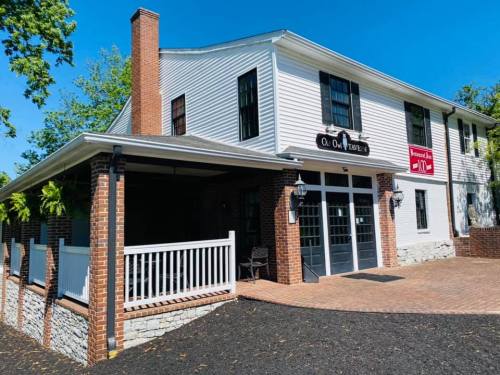 A charming two-story building with white siding, brick accents, and a welcoming porch on a sunny day.