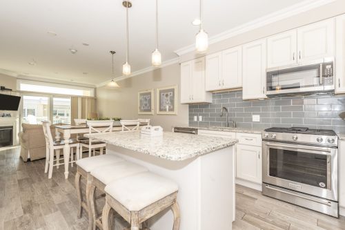 Modern kitchen with granite countertops, stainless steel appliances, and a dining area featuring light wood furniture.