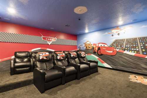 A cozy home theater with black recliners and colorful "Cars" themed wall murals.