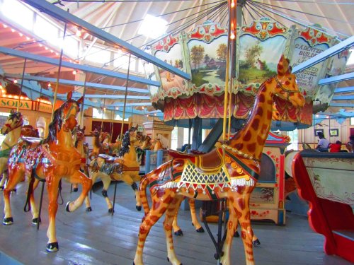 A colorful carousel featuring intricately painted horses and a giraffe, set in a vintage amusement park.