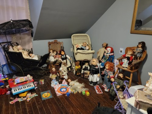 A cluttered room filled with various dolls, toys, and a vintage stroller, creating an eerie atmosphere.