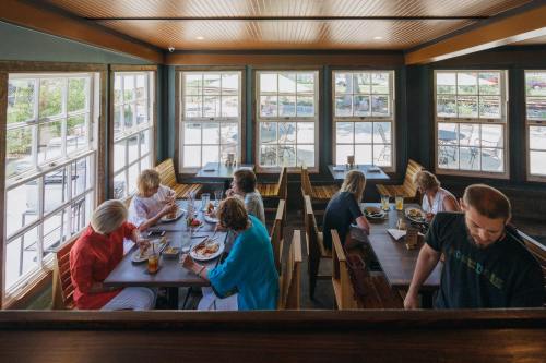 A cozy restaurant scene with diners enjoying meals at wooden tables, large windows letting in natural light.