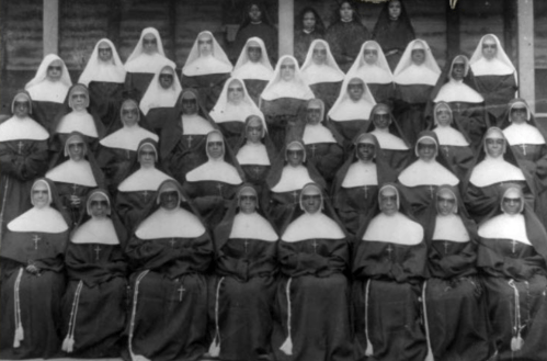 A large group of nuns in traditional habits, posing together in a historic black-and-white photograph.