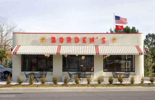Exterior of Borden's restaurant with a striped awning, outdoor seating, and an American flag flying above.