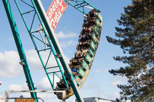 A group of people enjoying a thrilling ride on a large amusement park swing ride against a blue sky.