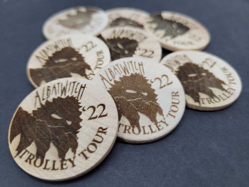 A collection of wooden tokens featuring a bearded figure and the text "Albatwitch Trolley Tour 22."