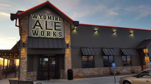 Exterior of Wyoming Ale Works building at dusk, featuring stone facade and illuminated sign.