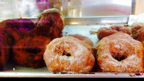 A tray of freshly made donuts, some coated in sugar, with a variety of shapes and colors.