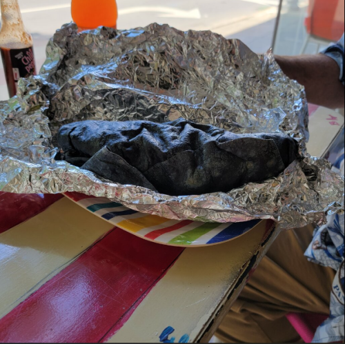 A plate with a foil-wrapped item, partially opened, resting on a colorful striped table.