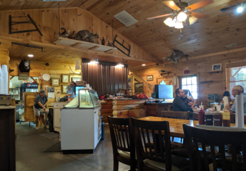 Interior of a rustic restaurant with wooden decor, tables, and patrons dining. Taxidermy animals are displayed on the walls.