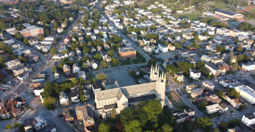 Aerial view of a town featuring residential areas, trees, and a prominent church with tall spires.