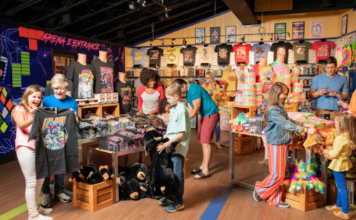 A vibrant store filled with colorful t-shirts and merchandise, with customers browsing and interacting.