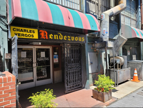 Entrance of Rendezvous restaurant with a sign reading "Charles Vergos," featuring a striped awning and nearby ventilation.