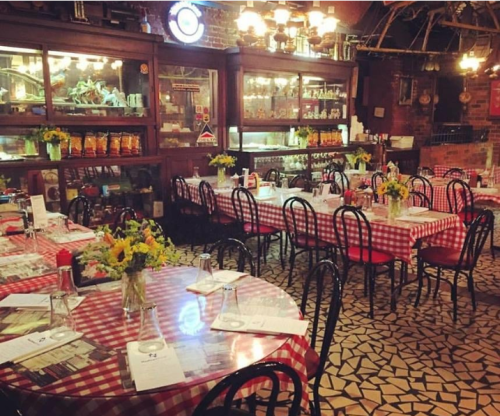 Cozy restaurant interior with checkered tablecloths, floral centerpieces, and warm lighting.