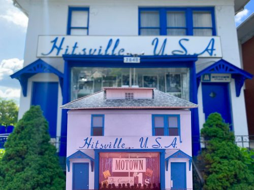 A model of Hitsville U.S.A. in front of the actual building, showcasing its iconic blue and white facade.