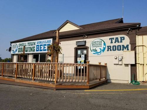 Exterior of Chetco Brewing Company with a tap room sign and a wooden deck, featuring a welcoming entrance.