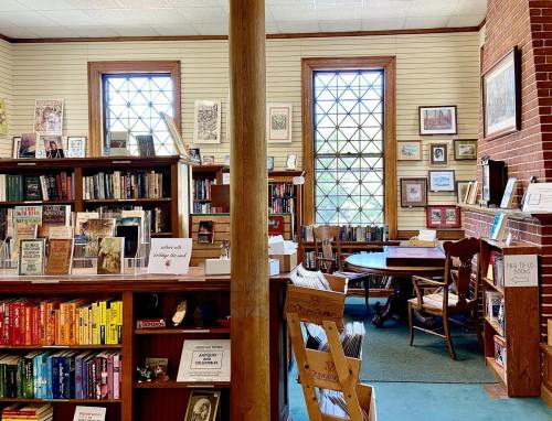 Cozy library interior with bookshelves, a wooden table, and large windows, creating a warm reading atmosphere.