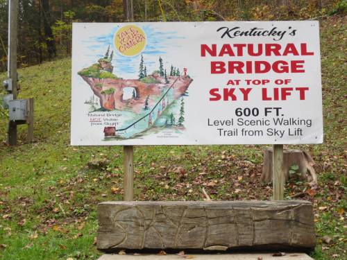 Sign for Kentucky's Natural Bridge at the top of Sky Lift, featuring a scenic walking trail and colorful illustrations.