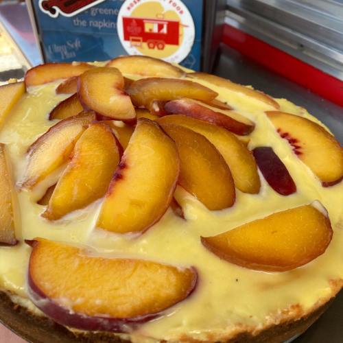 A close-up of a peach tart topped with fresh peach slices on a creamy filling.