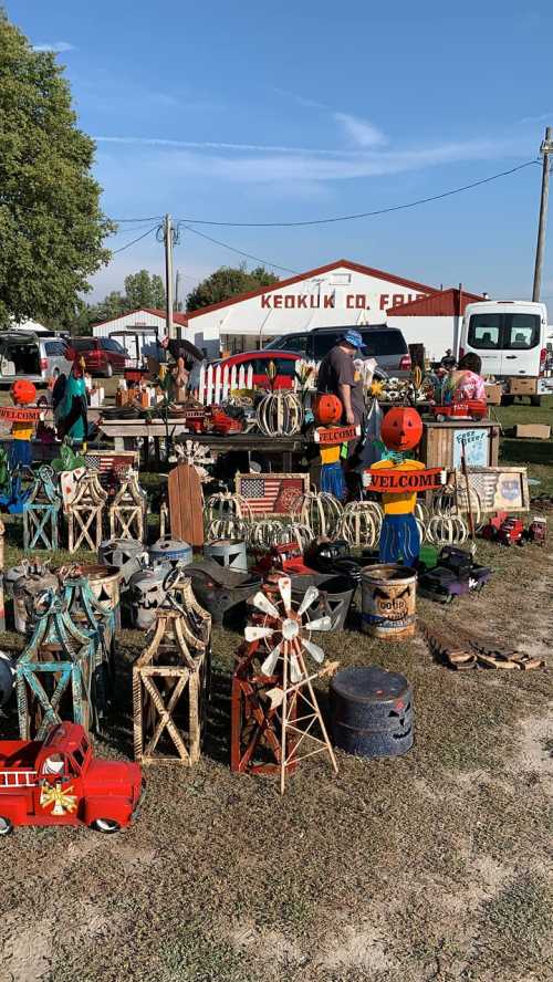 A bustling outdoor market with various decorative items, including pumpkins and rustic decor, under a clear blue sky.