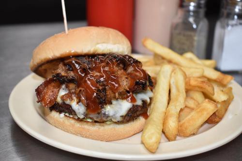 A juicy burger topped with grilled chicken and barbecue sauce, served with crispy fries on a plate.