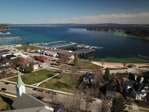 Aerial view of a lakeside town with marinas, docks, and residential areas along the water's edge.