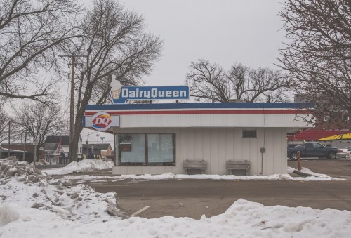 Dairy Queen building in winter, surrounded by snow, with a clear sky and trees in the background.