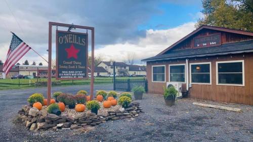 A rustic restaurant exterior with a sign reading "O'Neill's," surrounded by colorful pumpkins and flowers.
