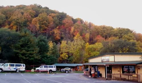 A scenic view of a parking lot with colorful autumn trees and a building in the foreground.