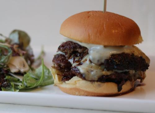 A juicy cheeseburger with melted cheese on a soft bun, served alongside a fresh salad.
