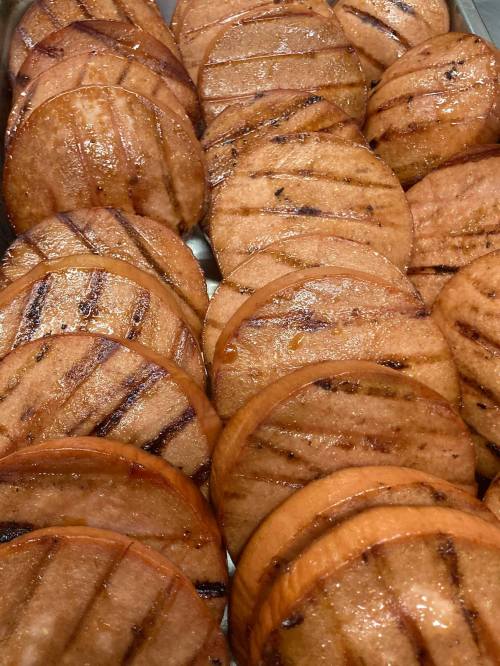 Grilled slices of sausage arranged neatly on a tray, showcasing their caramelized surface and grill marks.