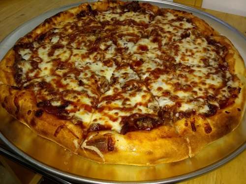A freshly baked pizza topped with melted cheese and savory meat, sliced and served on a metal tray.