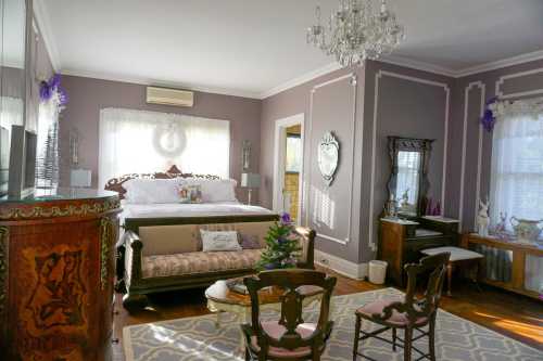 Cozy bedroom with a vintage bed, elegant decor, a chandelier, and a small Christmas tree on a table.