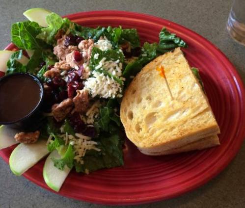 A colorful plate featuring a salad with greens, cranberries, cheese, and a side of toasted bread.