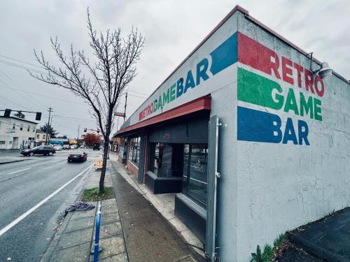 Exterior of a building with "Retro Game Bar" painted on the wall, located on a rainy street corner.