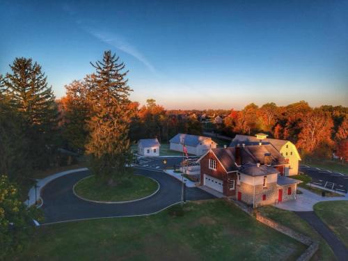 Aerial view of a small town with trees, houses, and a circular road, illuminated by warm autumn sunlight.