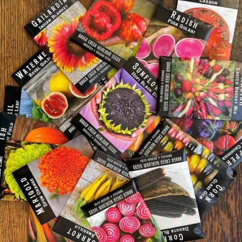A colorful assortment of seed packets featuring various flowers and vegetables scattered on a wooden surface.