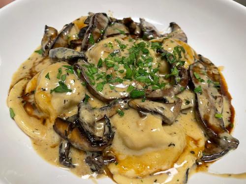 Creamy mushroom ravioli topped with sautéed mushrooms and fresh herbs in a rich sauce.