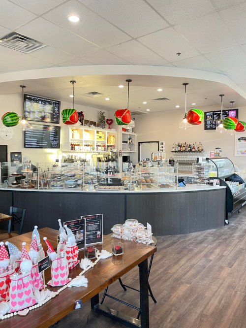 A cozy café interior with a display case of pastries, festive decorations, and a wooden table in the foreground.