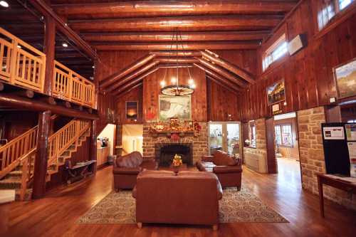 Cozy lodge interior with wooden beams, a stone fireplace, leather sofas, and a warm, inviting atmosphere.